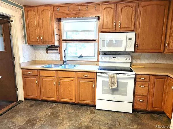 a kitchen with stainless steel appliances granite countertop a sink a stove and a refrigerator with wooden cabinets