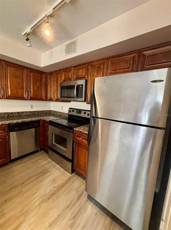 7320 Westpointe Boulevard, Unit 526 Orlando, FL 32835 - Photo 5 of 20 a kitchen with stainless steel appliances granite countertop a refrigerator a sink dishwasher a stove top oven a refrigerator and cabinets with wooden floor