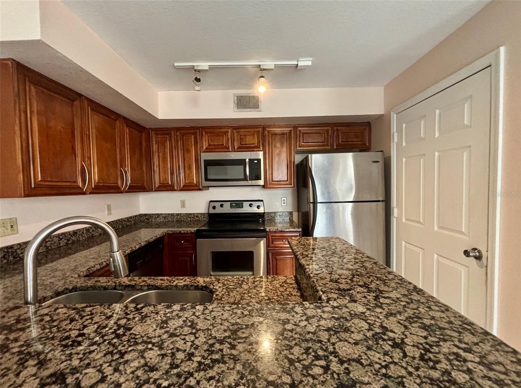 7320 Westpointe Boulevard, Unit 526 Orlando, FL 32835 - Photo 6 of 20 a kitchen with granite countertop a refrigerator stove top oven and sink