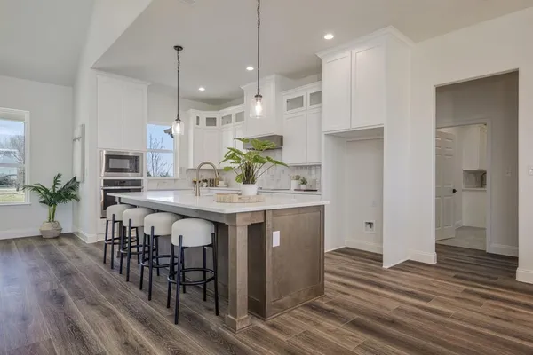 a kitchen with kitchen island granite countertop a sink cabinets and wooden floor