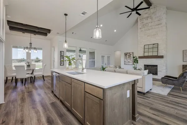 a large white kitchen with a white stove top oven a dining table and chairs with wooden floor