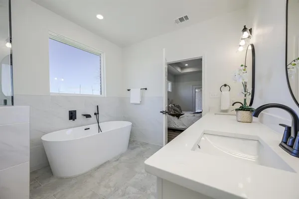 a bathroom with a double vanity sink bathtub and mirror