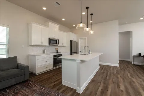 a large white kitchen with a large window a sink and stainless steel appliances