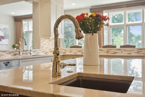 a kitchen with kitchen island granite countertop a table chairs sink and cabinets