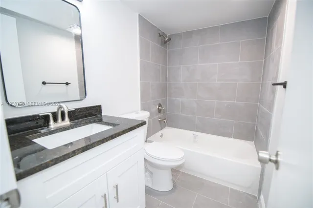 a bathroom with a granite countertop sink a toilet a mirror and shower