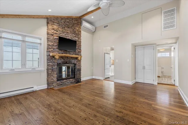an empty room with wooden floor fireplace and windows