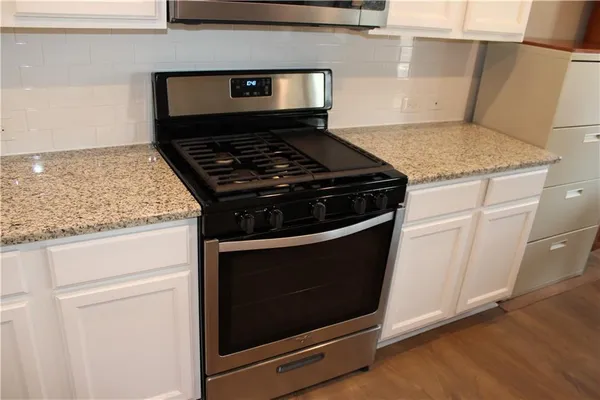 a kitchen with granite countertop white cabinets sink and window