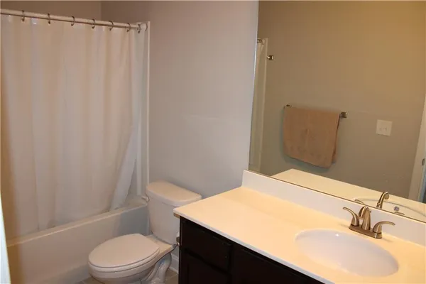 a bathroom with a granite countertop toilet and a sink