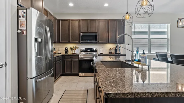 a kitchen with kitchen island granite countertop a sink a counter top space appliances and cabinets