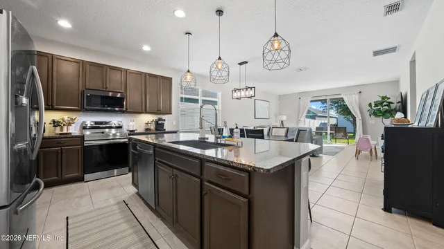 a kitchen with stainless steel appliances granite countertop a sink a stove a refrigerator cabinets and chairs