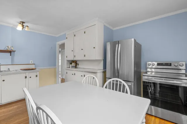 a kitchen with stainless steel appliances granite countertop a refrigerator a sink a stove and a dining table