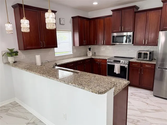 a kitchen with stainless steel appliances a dining table chairs refrigerator and microwave