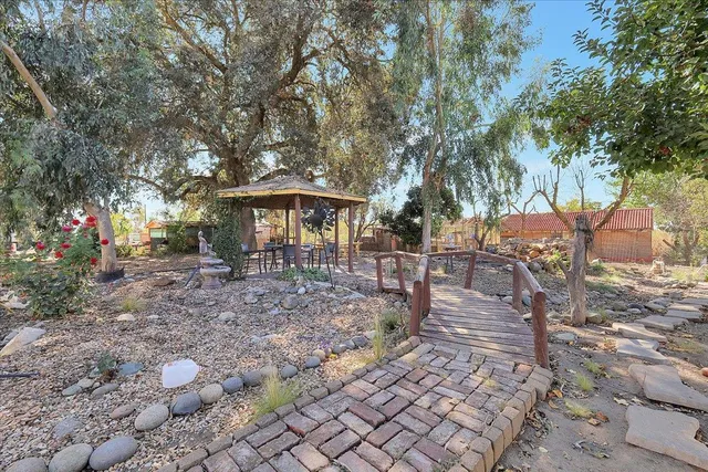 a view of a patio with table and chairs under an umbrella with large trees