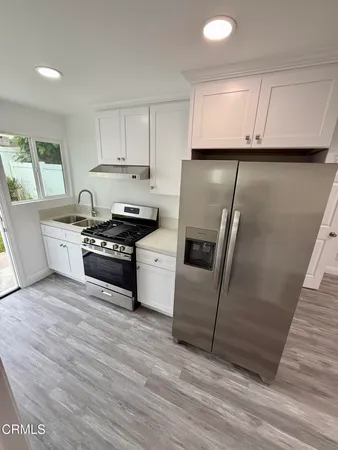 a kitchen with granite countertop a sink a stove and cabinets