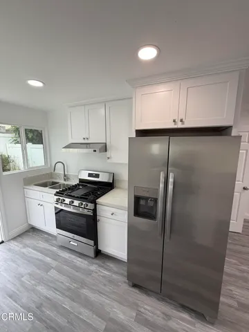 a kitchen with granite countertop a refrigerator stove and sink