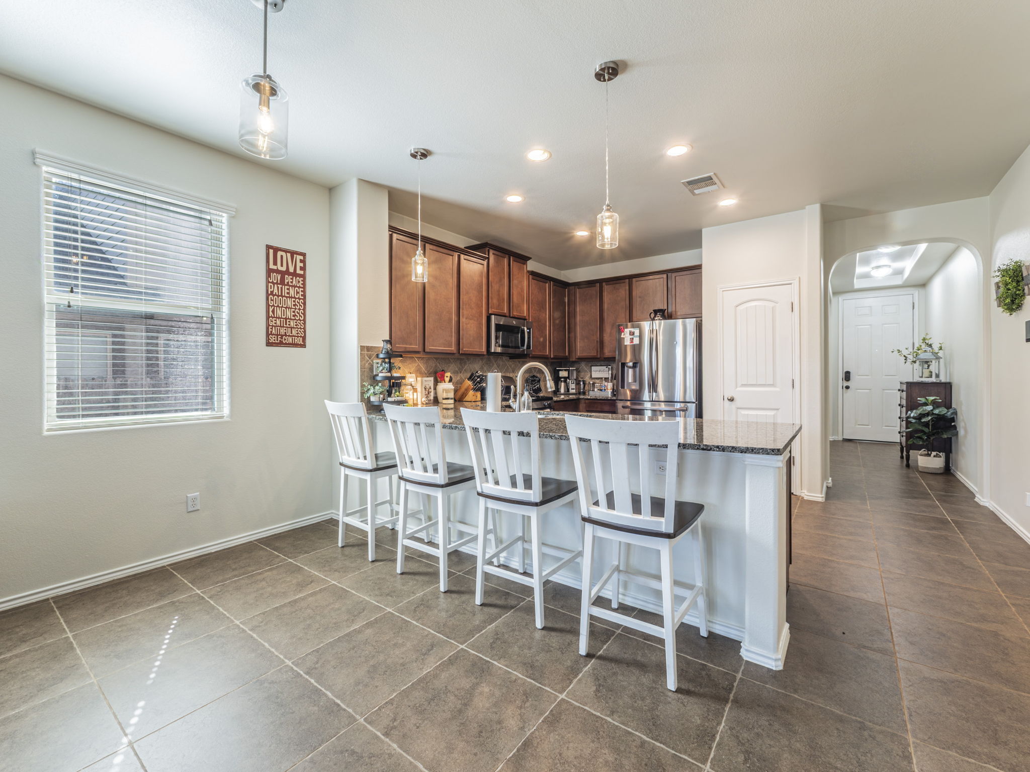 1366 Heep Run Buda, TX 78610 - Photo 4 of 35 Kitchen with a peninsula, a kitchen bar, arched walkways, stainless steel appliances, and decorative light fixtures