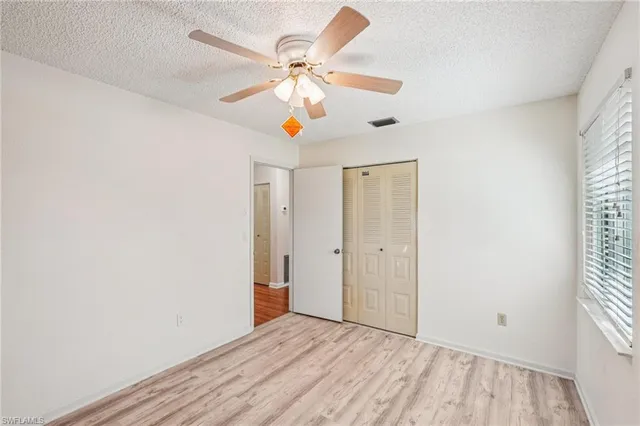 an empty room with a window and a ceiling fan