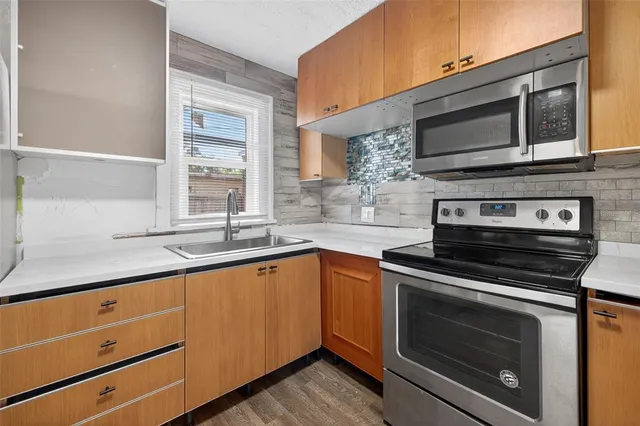 a kitchen with stainless steel appliances granite countertop a refrigerator a sink dishwasher a stove with wooden cabinets and floors