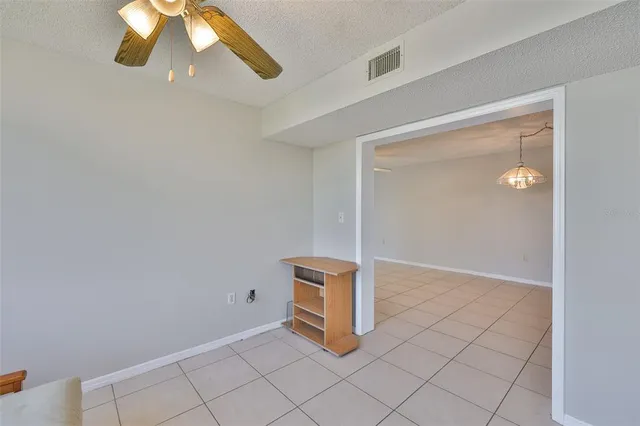 an empty room with a window and a chandelier fan