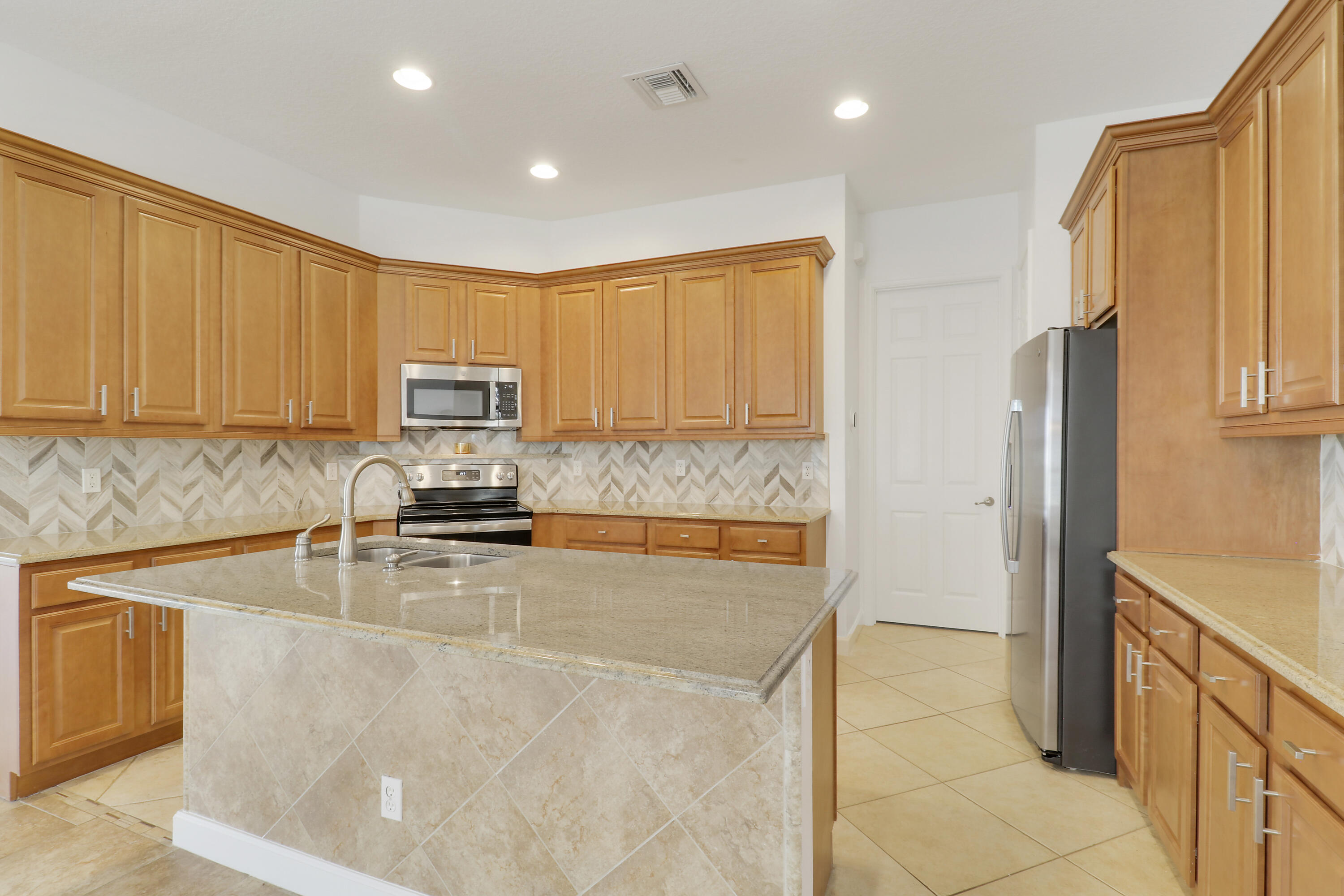 9212 Short Chip Circle Port St. Lucie, FL 34986 - Photo 12 of 71 a kitchen with stainless steel appliances granite countertop a refrigerator a stove top oven a sink and dishwasher