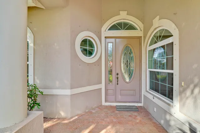 an empty room with wooden floor chandelier fan and windows