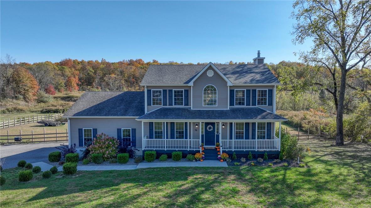 Colonial inspired home featuring a porch and a front lawn