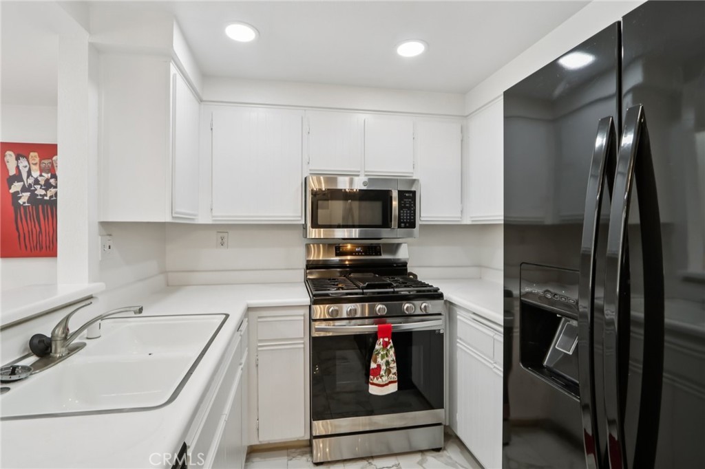 23605 Del Monte Dr., Unit 252 Valencia, CA 91355 - Photo 12 of 48 a kitchen with stainless steel appliances a stove a sink and a refrigerator