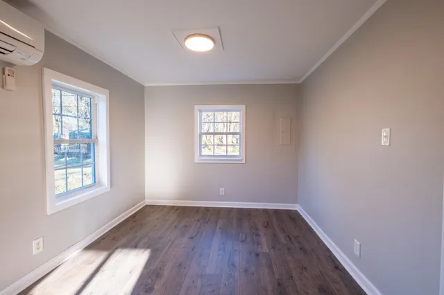 an empty room with wooden floor and windows