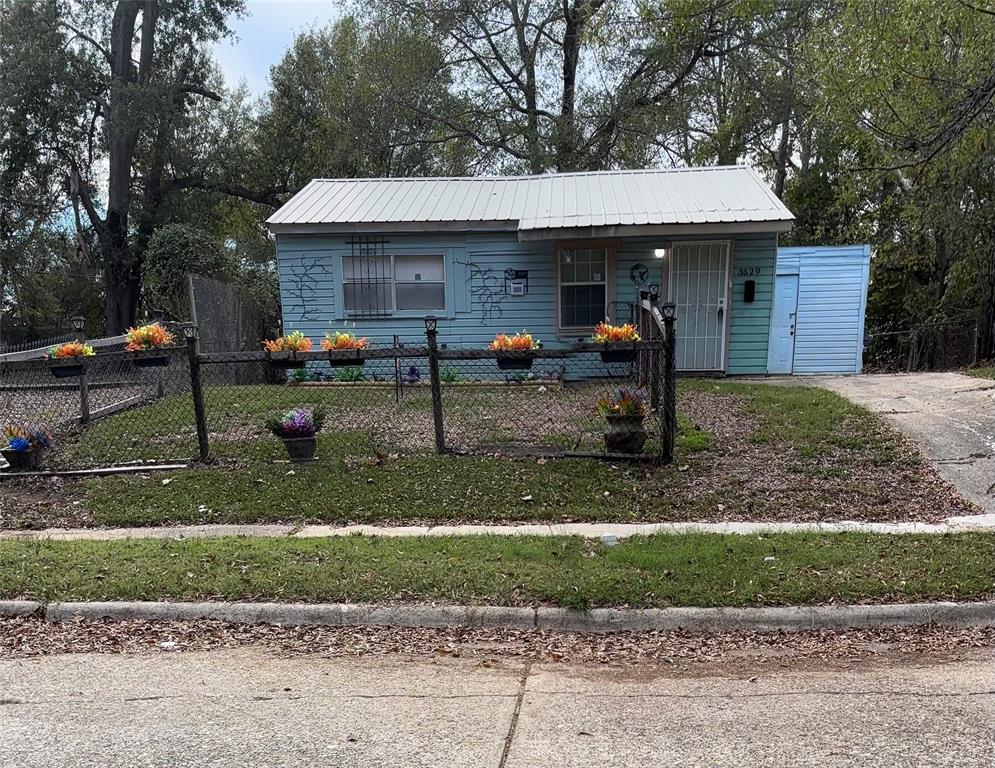 View of front of home with a fenced front yard, a metal roof, and a porch