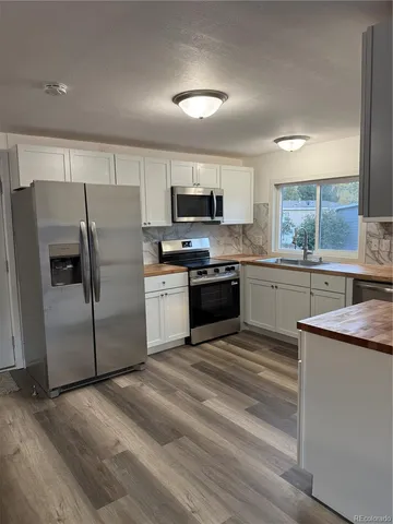 a kitchen with stainless steel appliances granite countertop a stove top oven a sink and a refrigerator