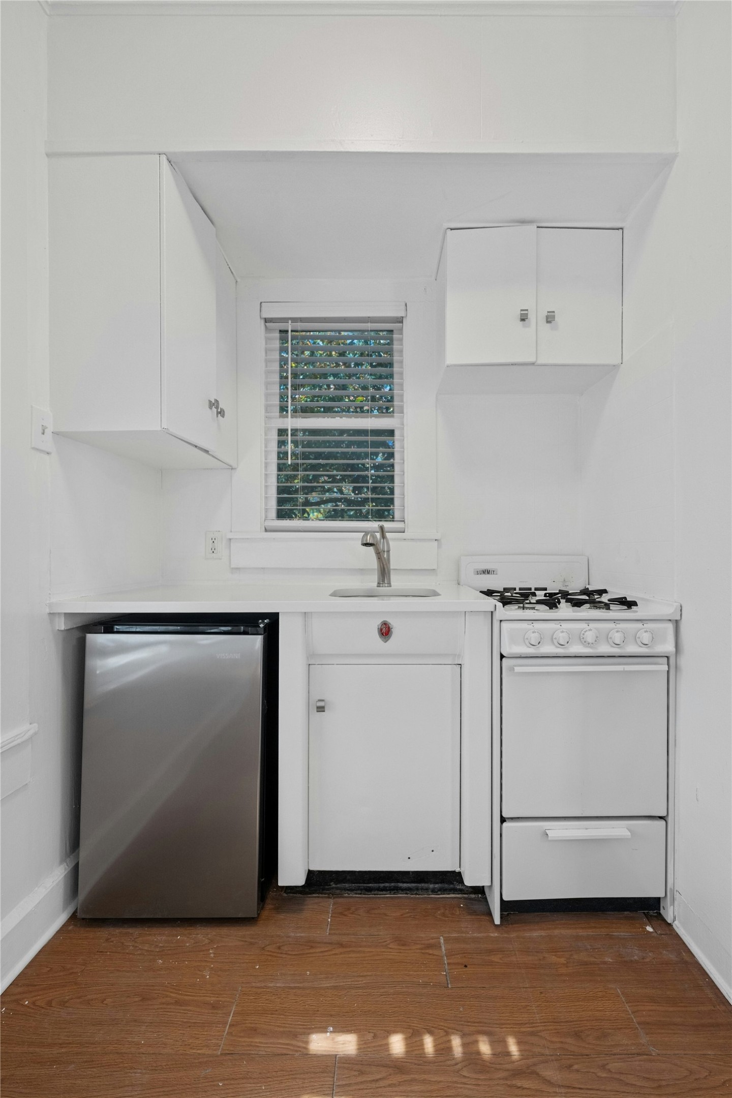 2201 Leon Street, Unit G Austin, TX 78705 - Photo 7 of 17 Compact kitchen featuring white cabinetry, a stainless steel mini-refrigerator, a gas range, wood-finish flooring, and a window with blinds