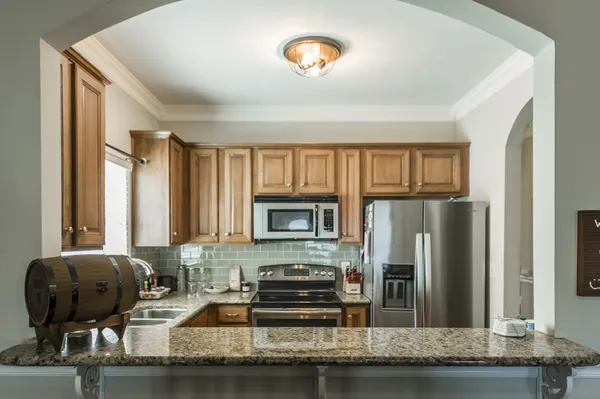 a kitchen with granite countertop a refrigerator and a stove top oven