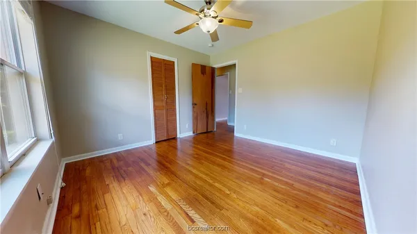 a view of an empty room with wooden floor and a window