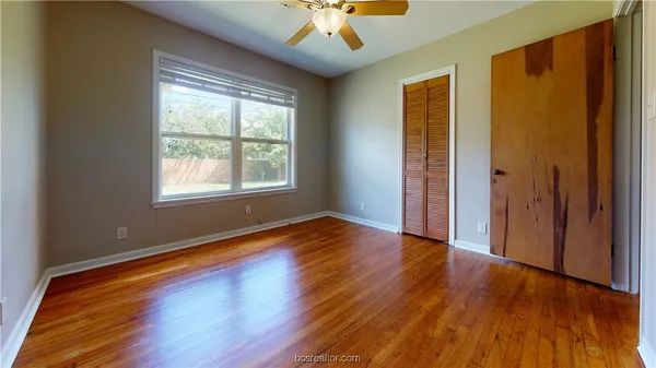 a view of an empty room with wooden floor and a window