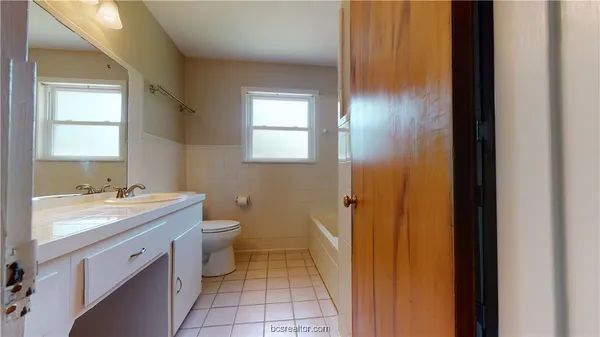 a bathroom with a granite countertop sink toilet and mirror