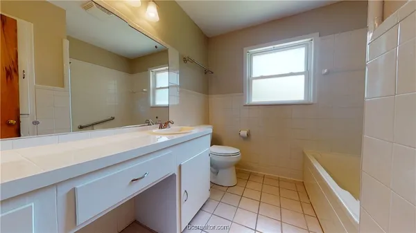 a spacious bathroom with a granite countertop sink a toilet and a mirror