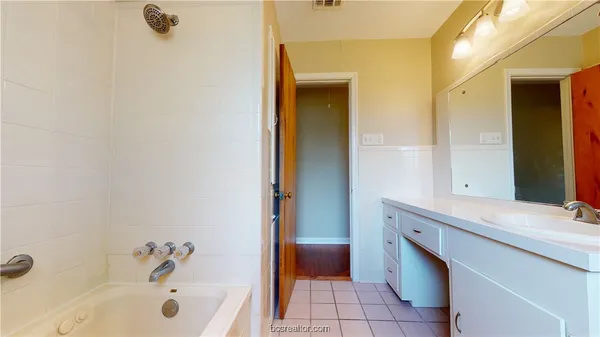 a bathroom with a tub sink and mirror