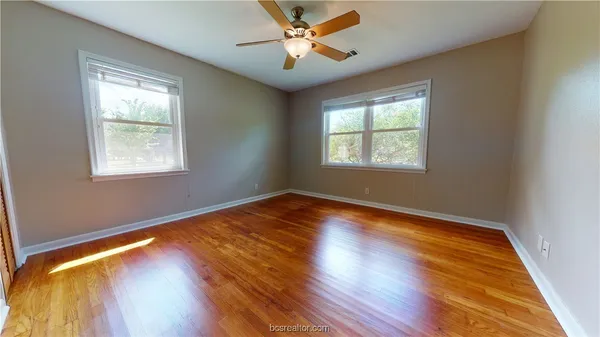 a view of empty room with wooden floor and fan