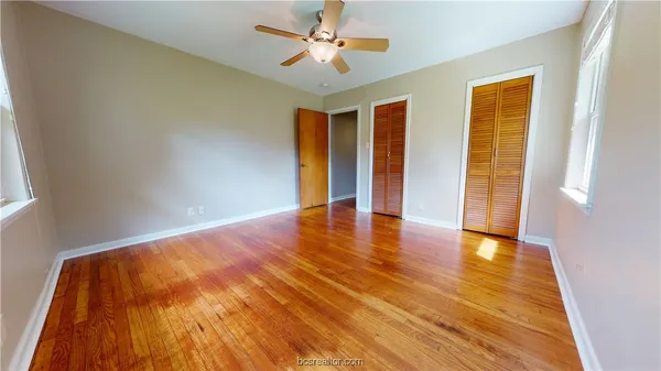 a view of an empty room with window and wooden floor