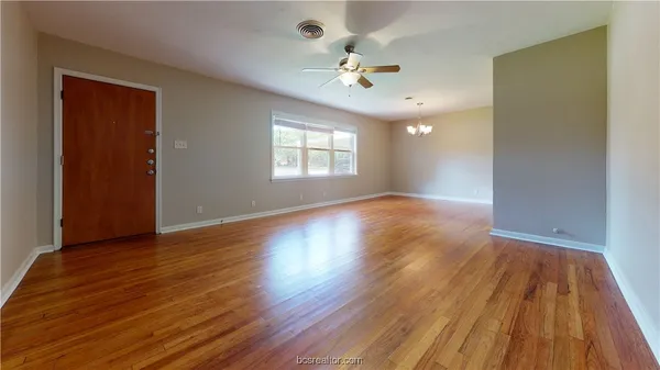 a view of an empty room with wooden floor and a window