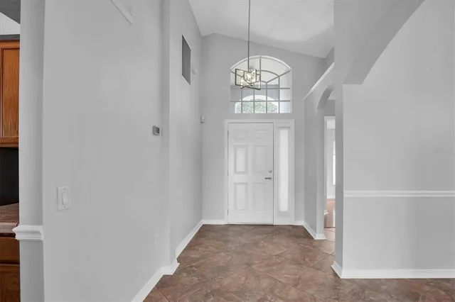 a view of an empty room with wooden floor and chandelier