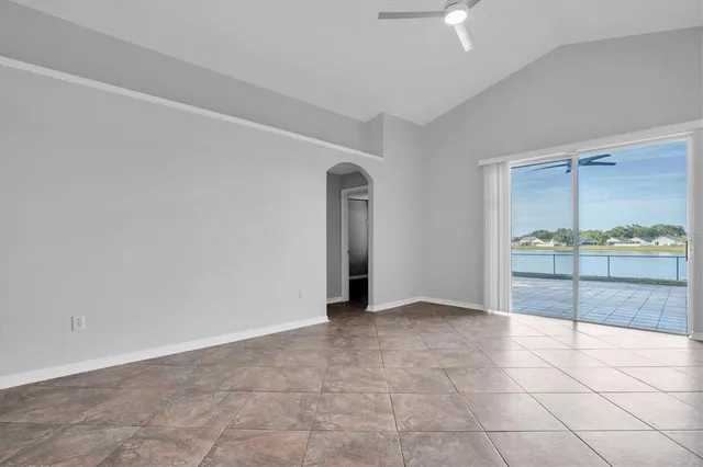 a view of an empty room and kitchen view with wooden floor