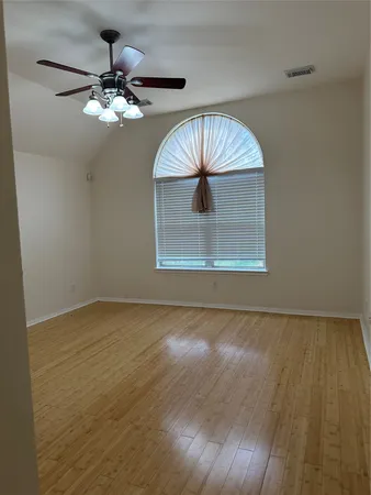 a view of an empty room with a chandelier fan and wooden floor