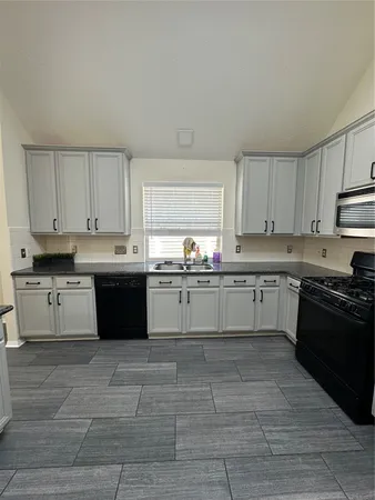 a large white kitchen with granite countertop white cabinets and stainless steel appliances