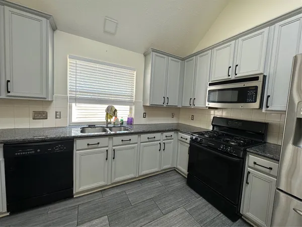 a kitchen with granite countertop cabinets stainless steel appliances and a sink