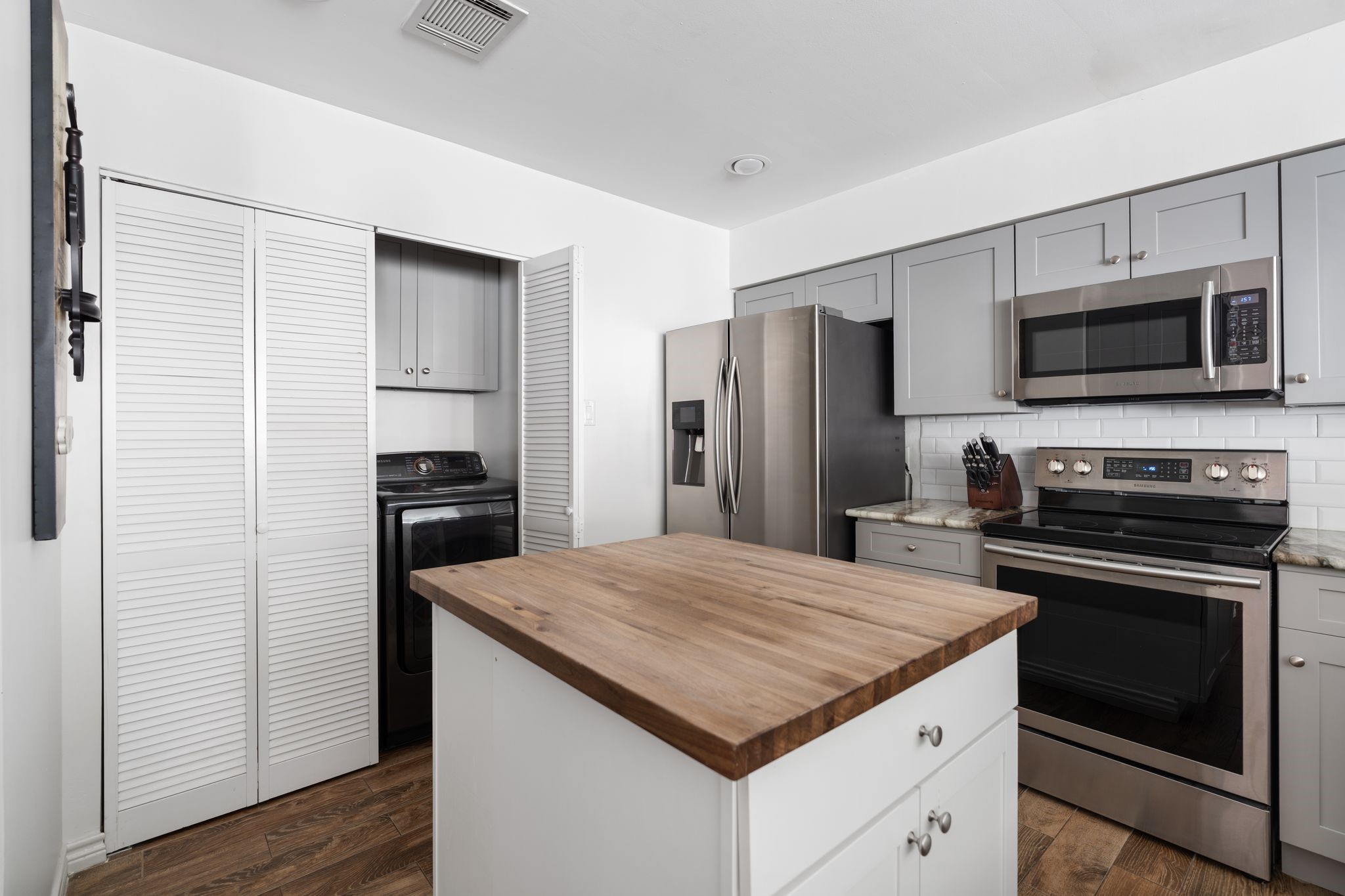 2612 Yupon Street Houston, TX 77006 - Photo 11 of 41 Full size washer and dryer with matching cabinetry are discreetly tucked into the kitchen, offering smart storage solutions without sacrificing valuable living space.