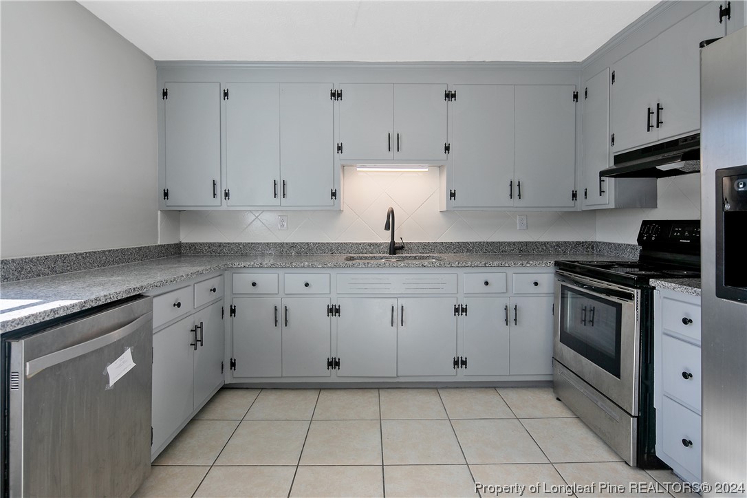 407 Ruth Street Spring Lake, NC 28390 - Photo 15 of 38 a kitchen with granite countertop a sink a stove and cabinets