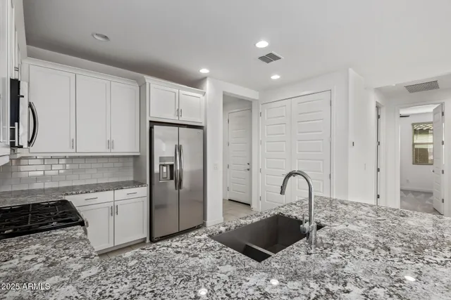 a kitchen with stainless steel appliances granite countertop a sink a stove and a refrigerator