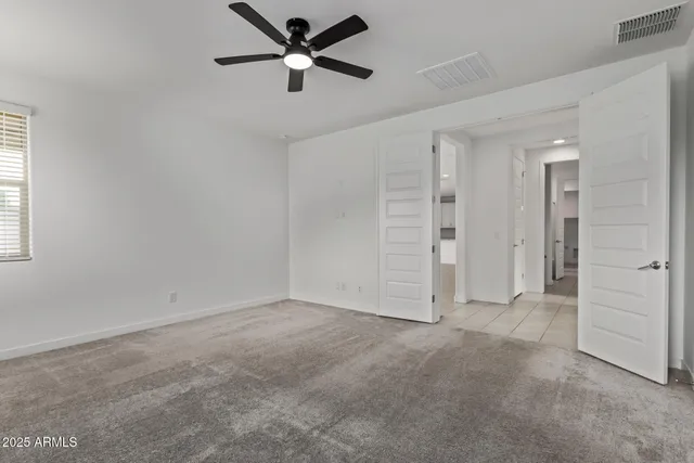 an empty room with closet and a ceiling fan
