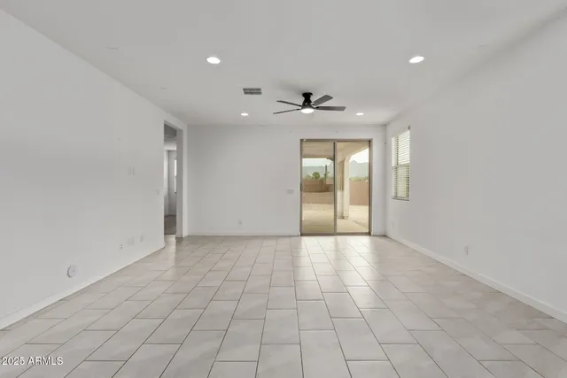 en empty room with windows and chandelier fan